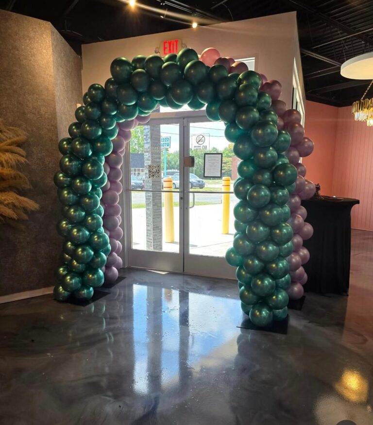 Green balloon arch decoration at an indoor entrance.