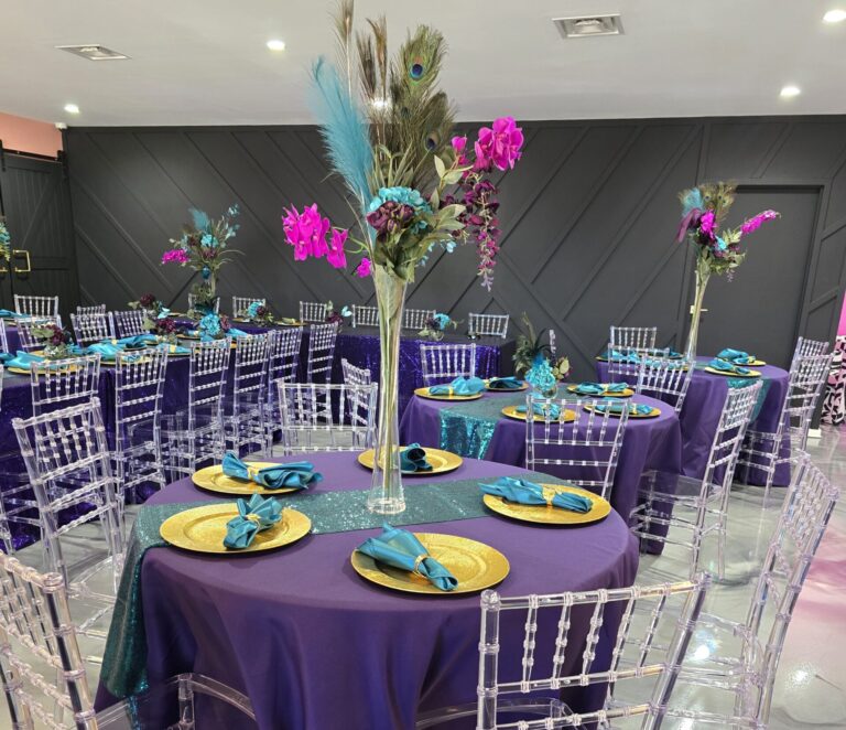 Elegant banquet tables with purple linens and clear chairs set for an event.