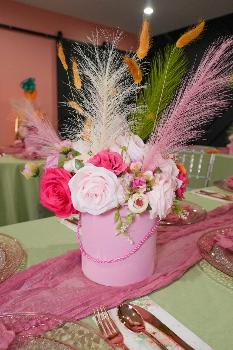 Elegant pink floral arrangement with feathers in a decorative vase.