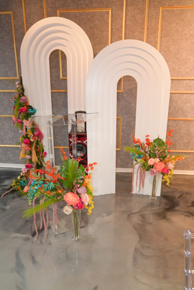 Colorful floral arrangements beside a modern archway and staircase.